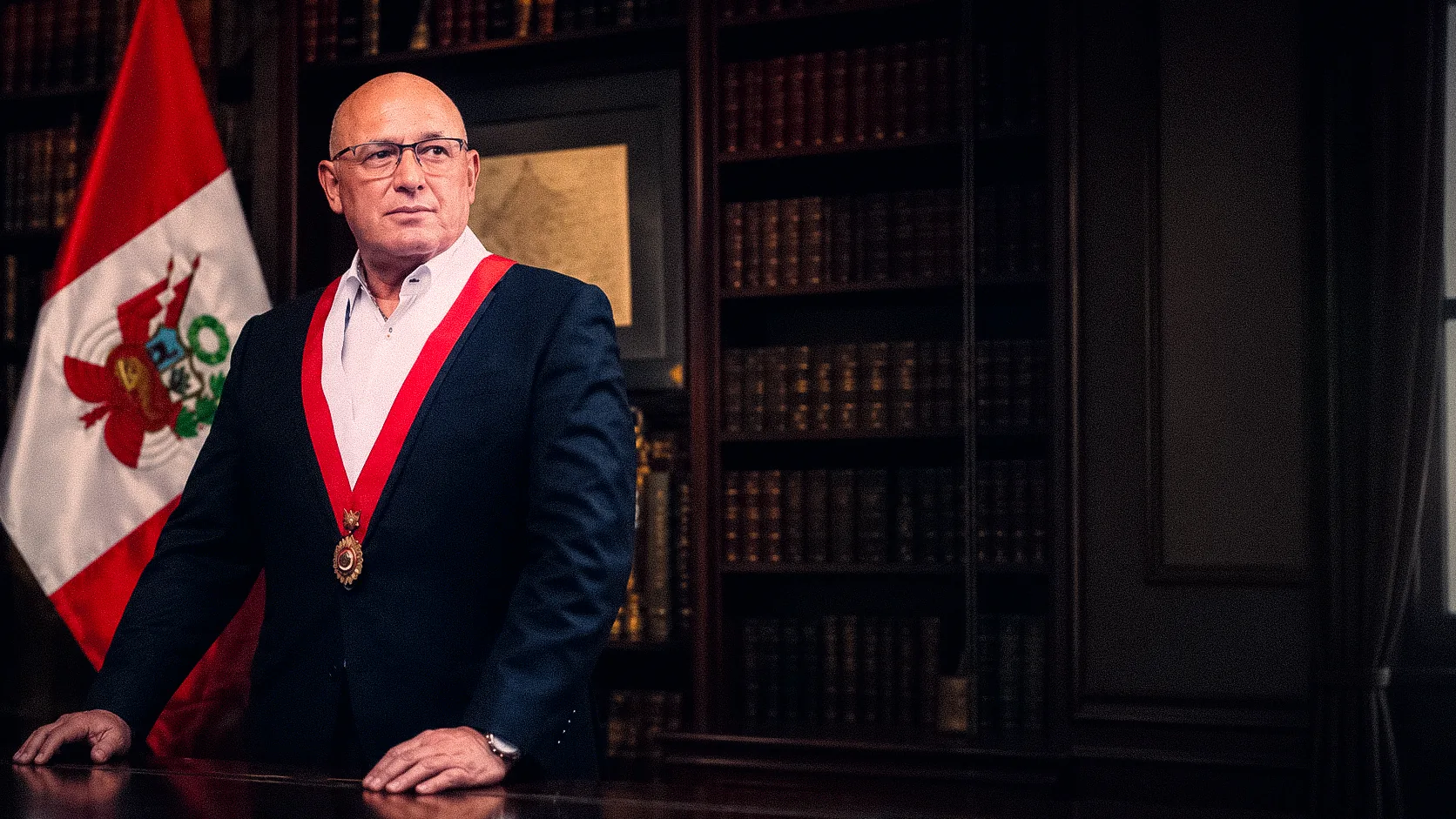 El Vicealmirante Calisto Giampietri con la banda presidencial junto a la bandera del Perú